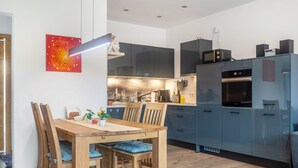 Eine moderne Küche mit dunklen Schränken, einem Holztisch und einem Stadtbild an der Wand.