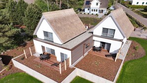 Een modern huis met twee verdiepingen, een groot terras en een apart zitgedeelte buiten.