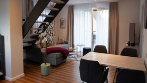 Een moderne woonkamer met een trap, een bank, een eettafel en een salontafel.