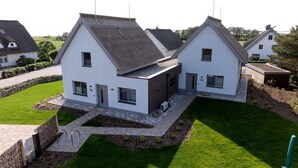 Een modern huis met twee verdiepingen, een schuin dak, een verzorgd gazon en een stenen pad naar de ingang.