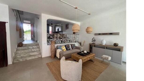 A modern living room with a sofa, coffee table, and a staircase leading to another area.