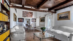 A living room with a white sofa, a glass coffee table, and a bookshelf. - Luxury Villa Nearby South Rome (Falcognana Di Sopra)