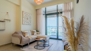 A modern living room with a sofa, coffee table, and decorative plants. - Azizi Riviera Residences - Meydan (Dubai)