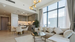 A modern living room with a sofa, coffee table, and dining area. - Azizi Riviera Residences - Meydan (Dubai)