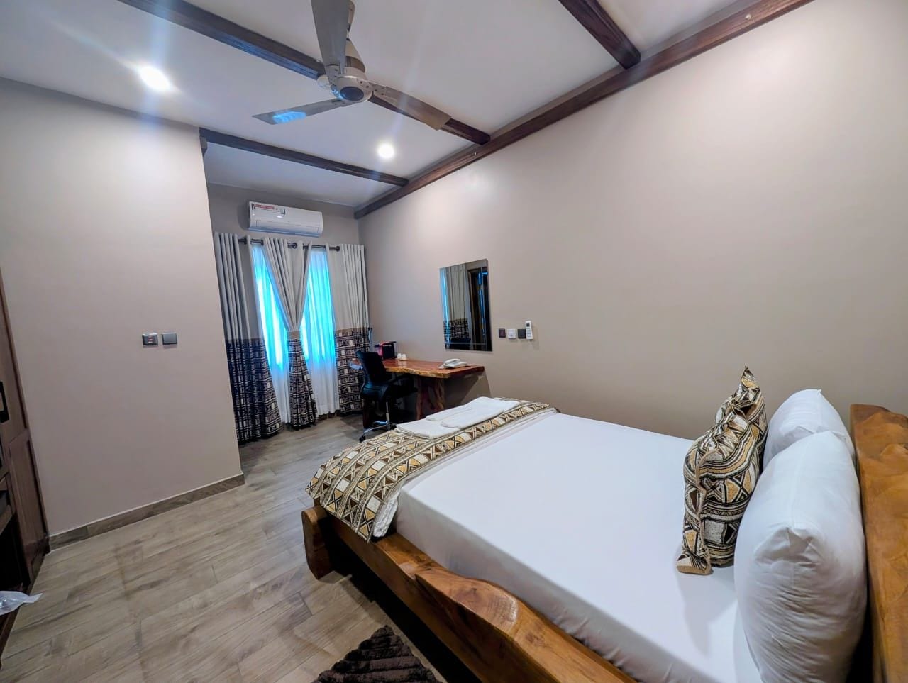 A bedroom with a bed, a desk, and a ceiling fan.