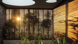 A modern interior with a stone wall, a wooden slatted window, and a circular light fixture. - Villa Mana | 7BR Tropical Estate Near Canggu Beach w/ Chef (Badung)