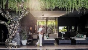 A modern indoor space with a seating area, a large tree, and a reflective pool. - Villa Mana | 7BR Tropical Estate Near Canggu Beach w/ Chef (Badung)