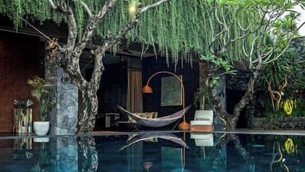 A serene indoor pool area with a hammock, stone walls, and lush greenery. - Villa Mana | 7BR Tropical Estate Near Canggu Beach w/ Chef (Badung)