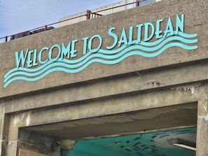 Une structure en béton sur laquelle on peut lire les mots « BIENVENUE À SALIDEAN », le tout surmonté d’un motif ondulé.