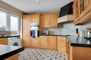 Una cocina con armarios de madera, horno integrado, microondas y lavadora.