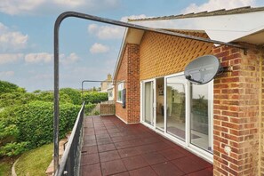 A balcony with a red-tiled floor, a brick wall, and a satellite dish.