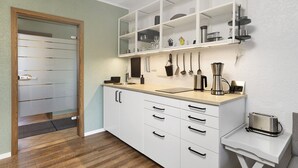 A modern kitchen with white cabinets, a wooden countertop, and a built-in shelf above the sink.