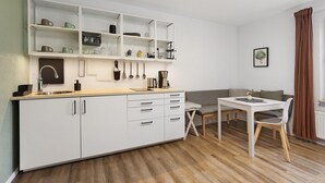 A modern kitchen with white cabinetry, a dining table, and a sofa.