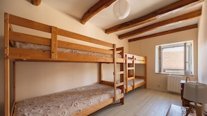 A room with two bunk beds, a radiator, a window with a view, and a lamp on a table.