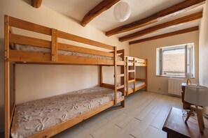 A room with two bunk beds, a radiator, a window with a view, and a lamp on a table.
