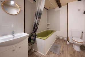 Et badeværelse med en hvid vask, et grønt badekar og et hvidt toilet.