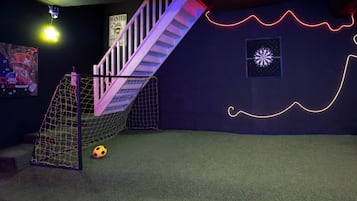 Een kamer met een voetbaldoel, een trap en een muur met neonverlichting.