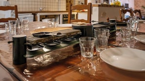 A dining table set with a portable stove, glasses, plates, and cutlery.
