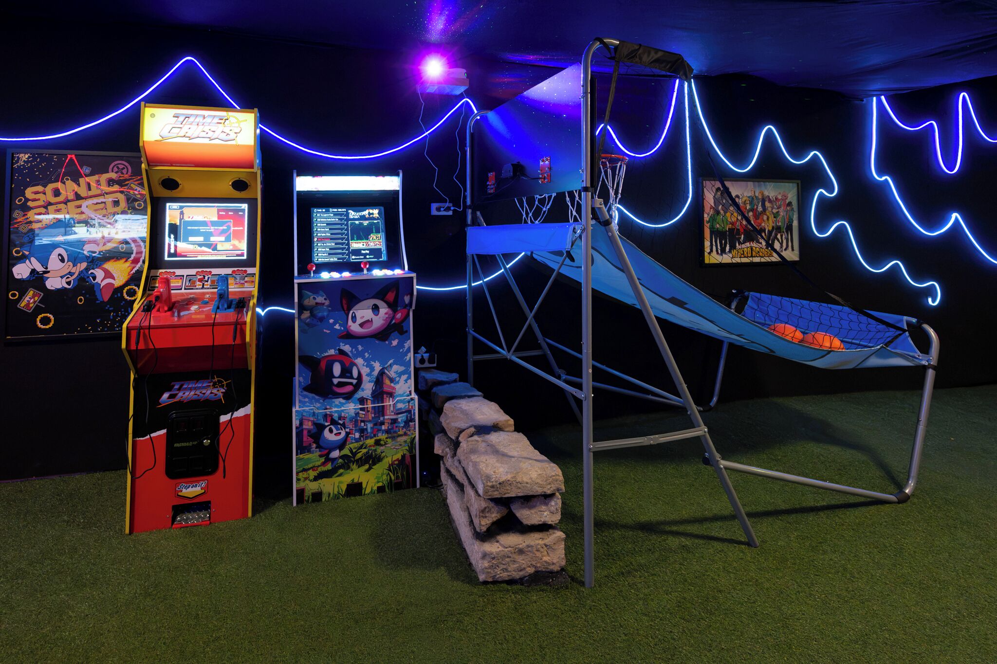 Ein Spielbereich mit Spielautomaten, einer Kletterstruktur und einer neonbeleuchteten Wand.