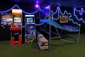 A gaming area with arcade machines, a climbing structure, and a neon-lit wall.
