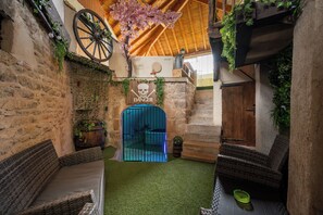 A rustic interior with stone walls, a wooden ceiling, and a blue gate marked 'DANGER'. - 70 m² Loft for 4 People* in the Jura - Patio & Arcade Room (Val Suran)