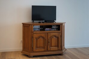 A wooden entertainment center with a flat-screen TV, DVD player, and various video games. - 70 m² Loft for 4 People* in the Jura - Patio & Arcade Room (Val Suran)