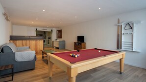 A cozy living room with a pool table, a grey sofa, and a wooden cabinet. - 70 m² Loft for 4 People* in the Jura - Patio & Arcade Room (Val Suran)