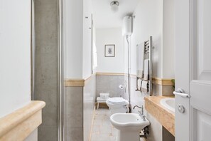 Un baño estrecho con inodoro, bidé y lavabo.
