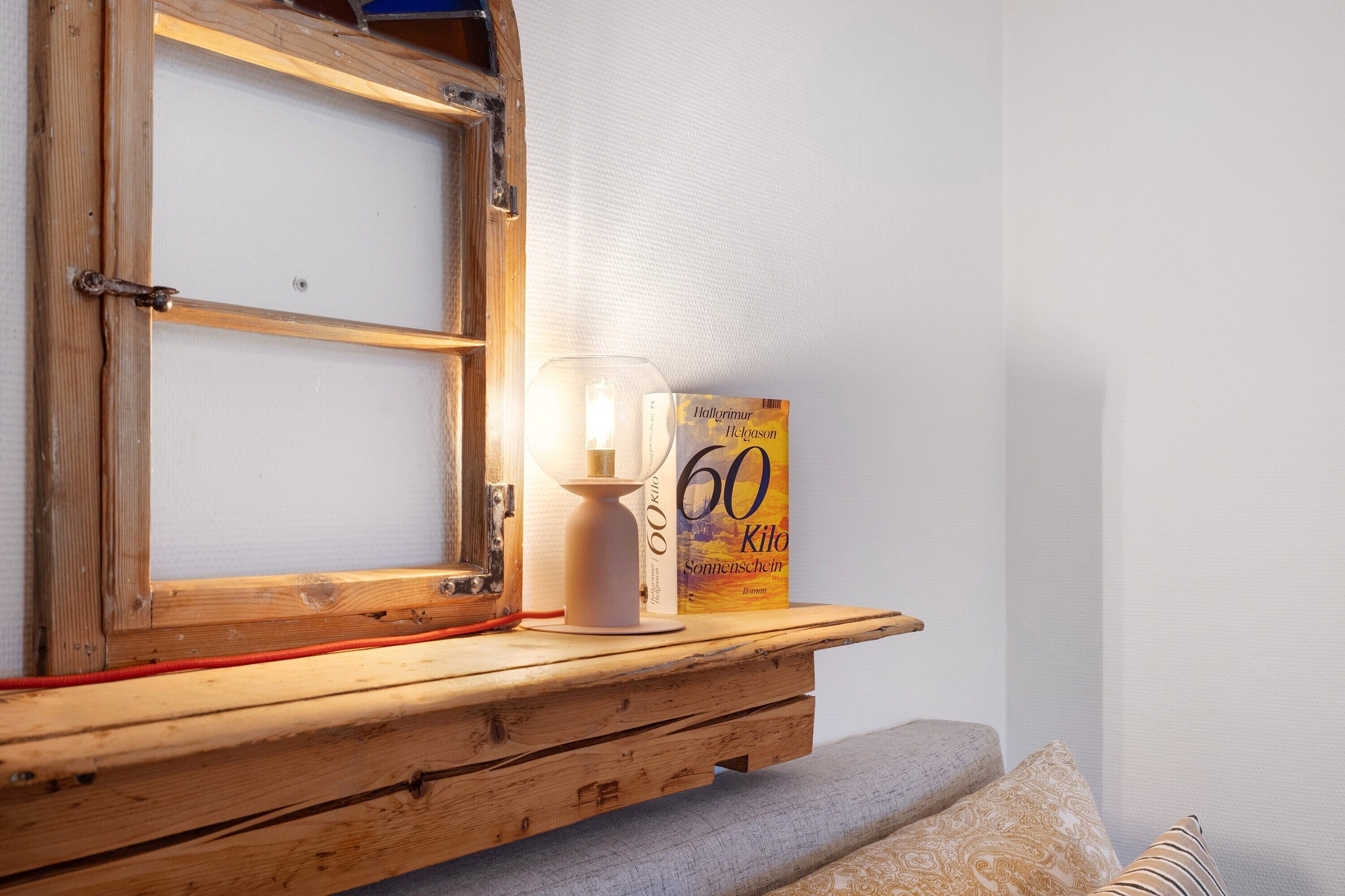 Una estantería de madera con un libro titulado '60 Kilogram Sonnenschein' y un candelabro con una vela encendida.
