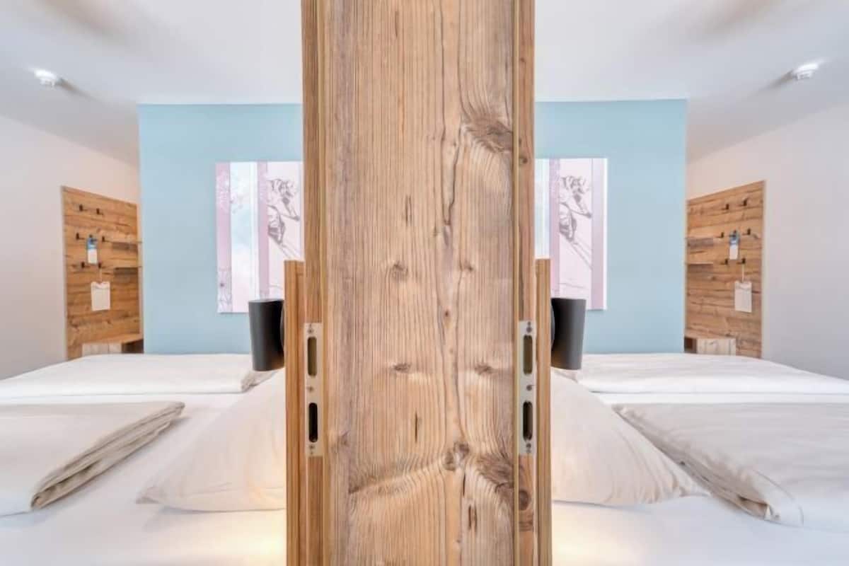 Ein Hotelzimmer mit zwei Betten, einer Wand mit Holzverkleidung und Bildern an den Wänden.