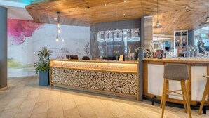 En reception med træloft, stenvæg og et skilt der siger "COFFEES".