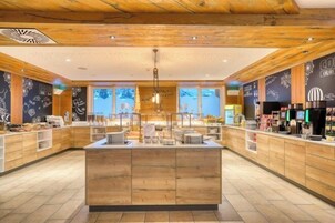 Un café moderno con detalles de madera, una isla central con asientos y paredes de pizarra con los artículos del menú.