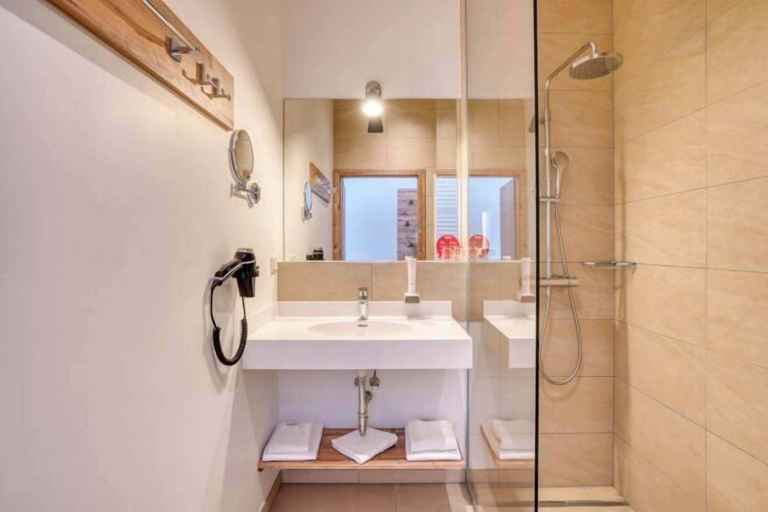 Ein modernes Badezimmer mit Duschkabine aus Glas, einem weißen Waschbecken und einem Spiegel.