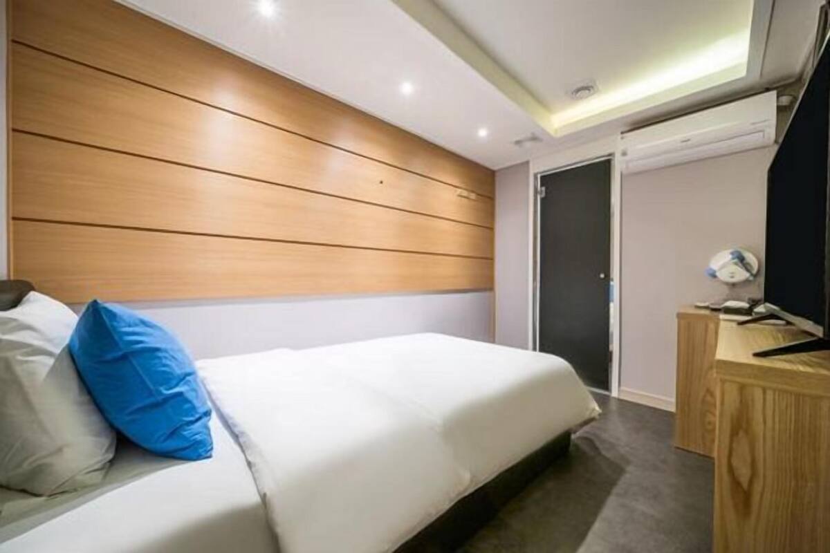 A hotel room with a bed, a desk, and a door.