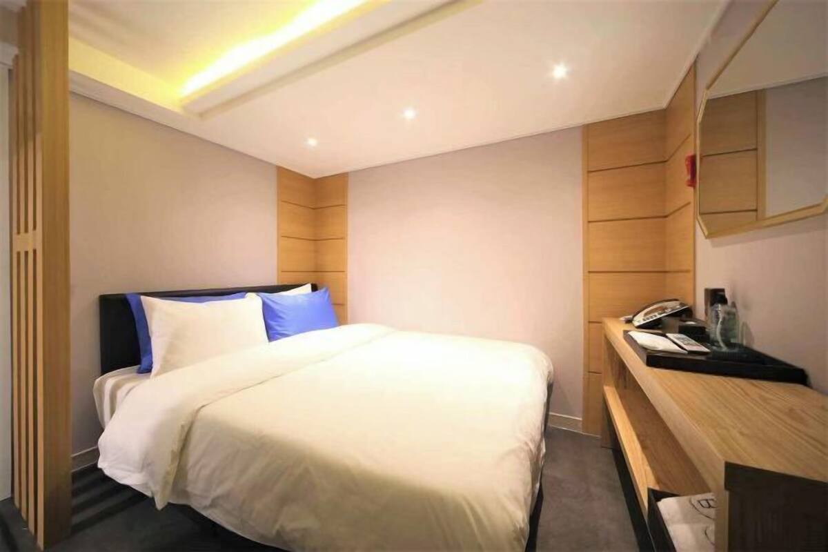 A hotel room with a bed, a desk, a telephone, and a mirror.