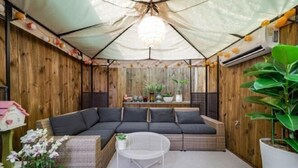 Une pièce chaleureuse avec un mur en bois, un canapé gris, une table blanche et une grande plante en pot.