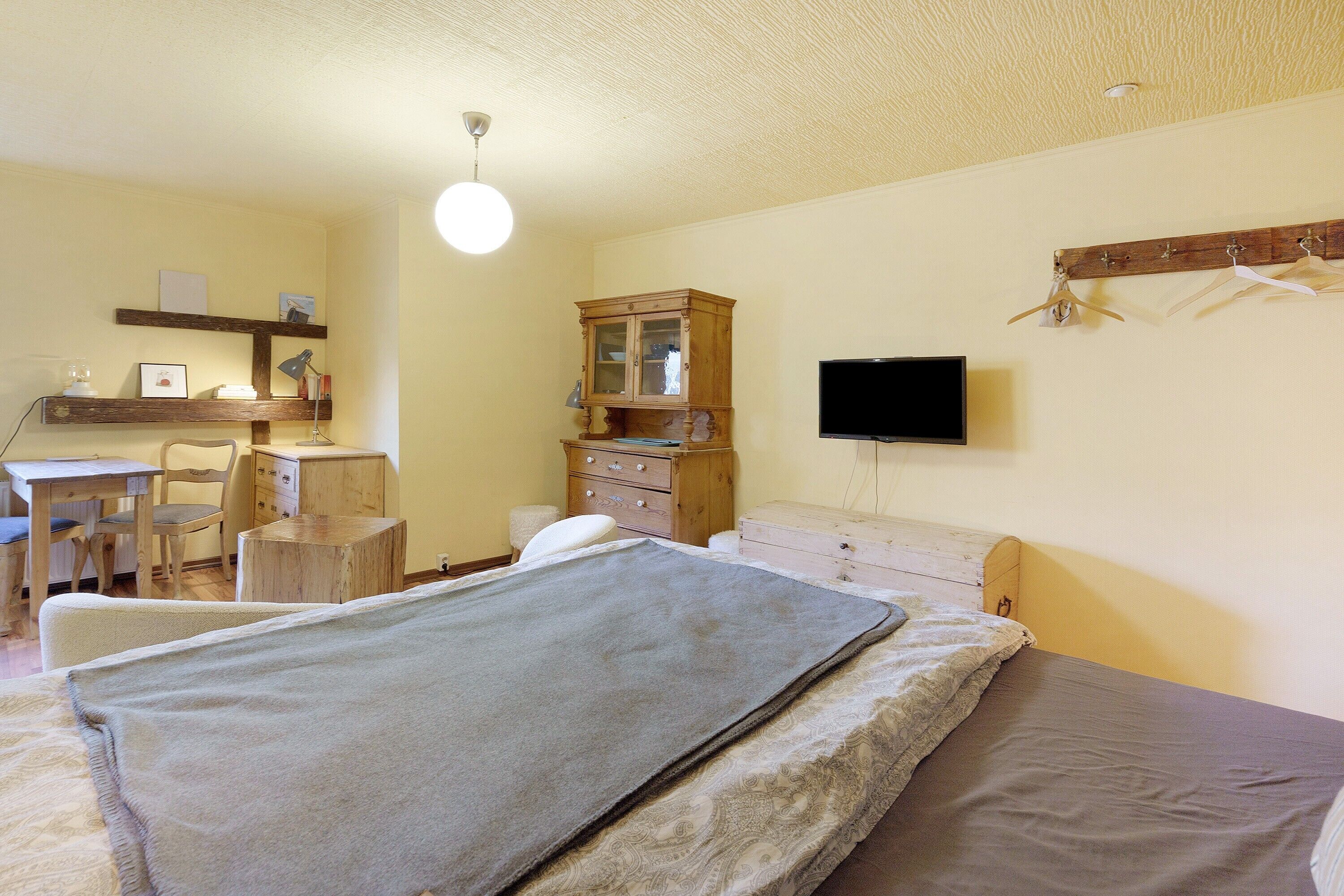 Ein Schlafzimmer mit Bett, Schreibtisch, Stuhl, Kommode, Fernseher und Kleiderschrank.