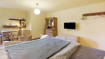 Ein Schlafzimmer mit Bett, Schreibtisch, Stuhl, Kommode, Fernseher und Kleiderschrank.