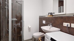 A modern bathroom with a glass shower enclosure, a toilet, a sink, and a washing machine. - Apartment 'Nahe Blauen Wunder' with Shared Terrace, Shared Garden and Wi-Fi (Dresden)