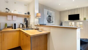 A modern kitchen with wooden cabinets, a built-in stove, a sink, and a flat-screen TV mounted above the counter. - Apartment 'Nahe Blauen Wunder' with Shared Terrace, Shared Garden and Wi-Fi (Dresden)
