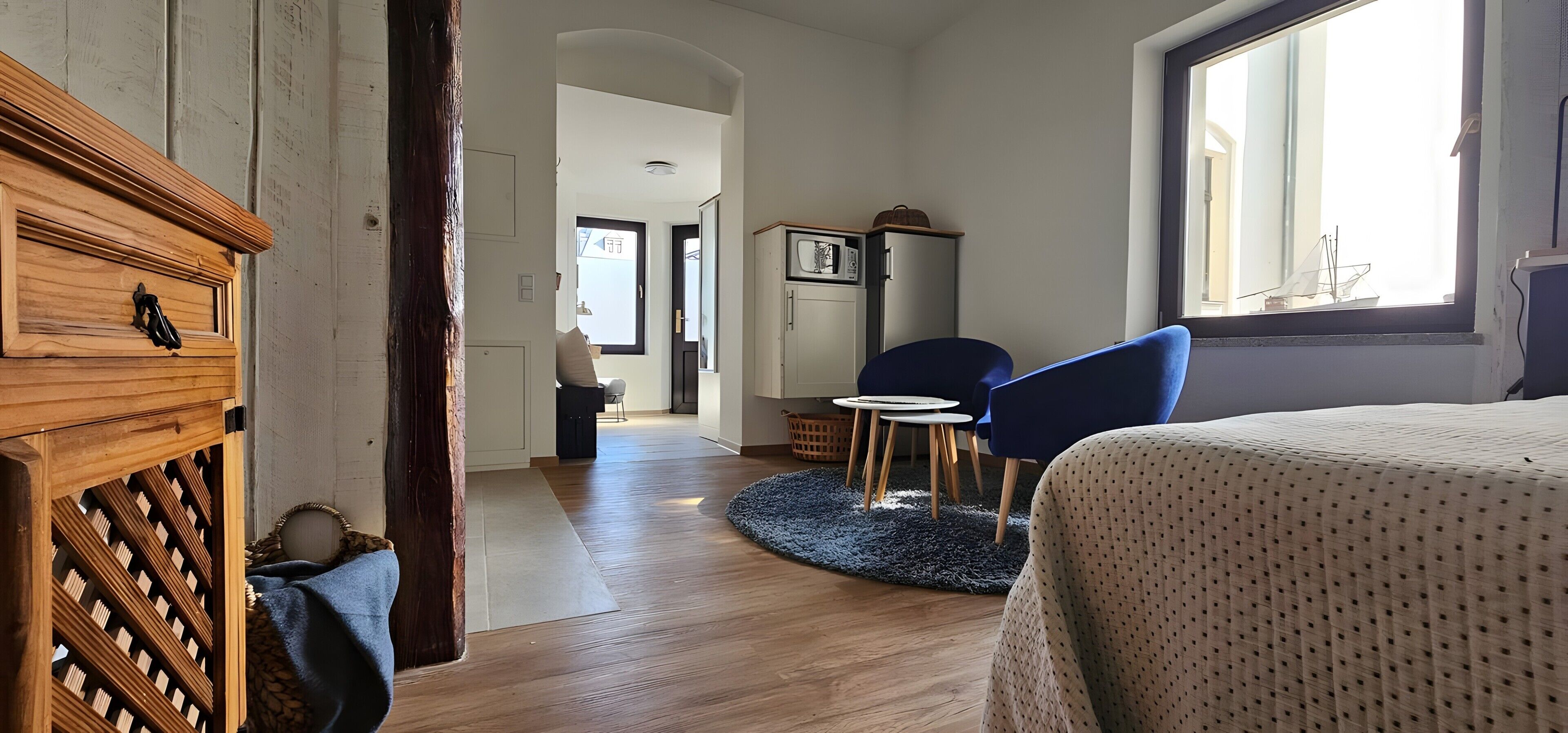 Une pièce comprenant un lit, une armoire en bois, un four à micro-ondes, une petite table et une chaise.