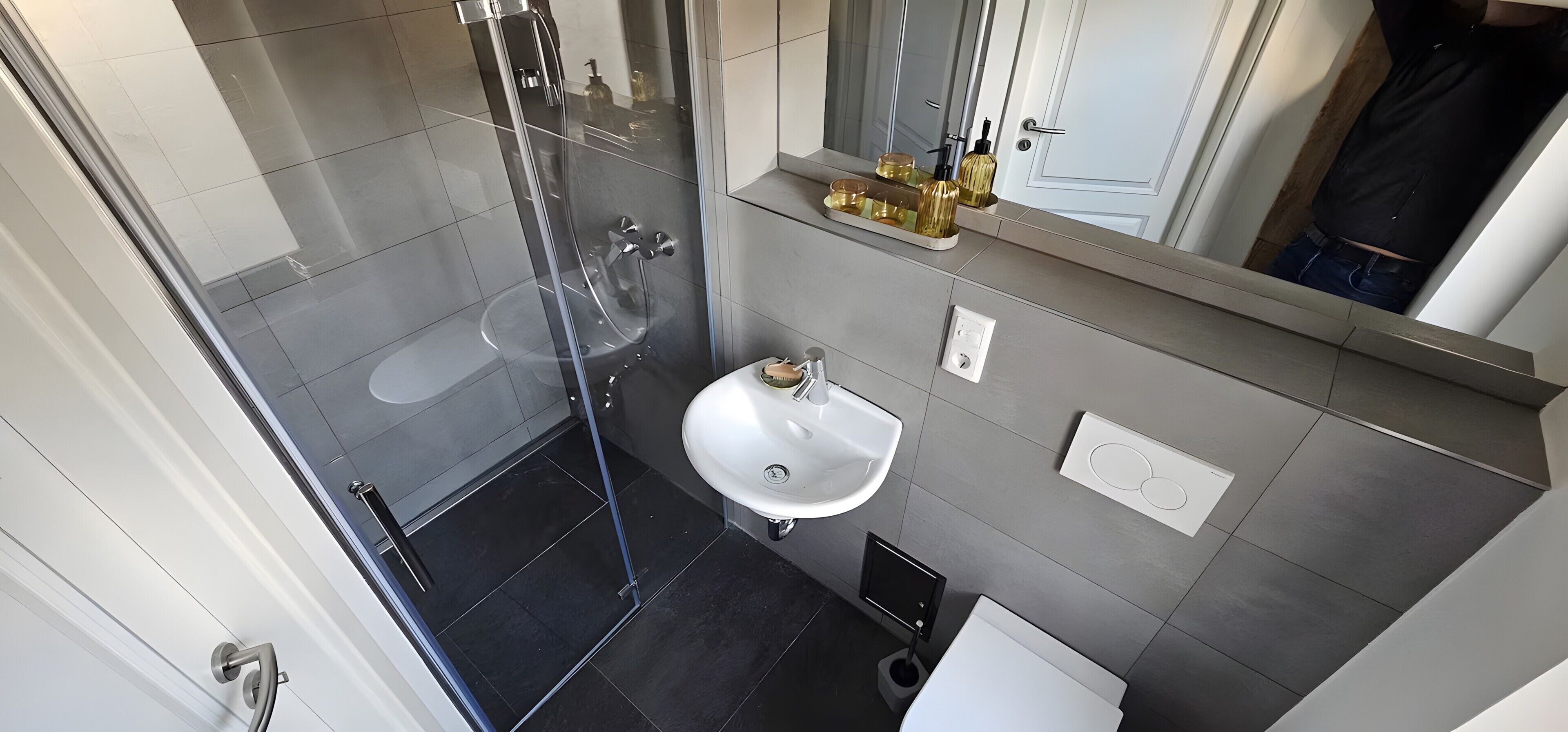 Une salle de bain moderne avec une douche à parois de verre, un lavabo blanc et des toilettes.