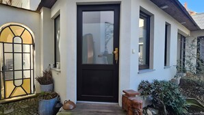 A house with a black front door, a large arched window, and a potted plant beside the door. - Apartment 2 'Near Blue Wonder' with Shared Terrace, Garden and Wi-Fi (Dresden)