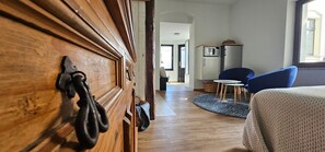 Une pièce comprenant une armoire en bois, un lit, une chaise bleue, une petite table et un four à micro-ondes posé sur un meuble.
