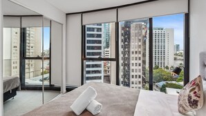 Ein modernes Hotelzimmer mit einem großen Bett, Blick auf Stadtgebäude und einem Balkon.