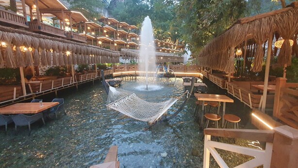 A water feature in the center of a courtyard with wooden seating and tables.
