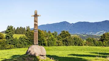 Una cruz de piedra en un campo cubierto de hierba, con montañas al fondo.