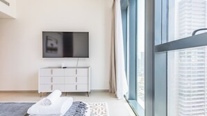A modern hotel room with a large window, a flat-screen TV, a white dresser, and a neatly made bed. - BLVD Heights Residences - Downtown (Dubai)