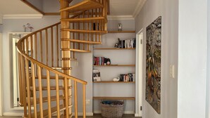 A wooden spiral staircase in a room with a bookshelf and a painting on the wall. - 8@Lalandi Beachfront Cottage Langstrand 15km between Swakopmund & Walvis Bay (Langstrand)