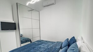 Um quarto moderno com uma cama, uma TV de tela plana e um espelho grande.